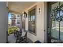 Inviting porch featuring rocking chairs, decorative pillows, and a stylish wreath on the front door at 97 Westerly Blvd, Erie, CO 80516