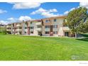 Condominium building with multiple balconies overlooking lush green lawns at 10211 Ura Ln # 104, Thornton, CO 80260
