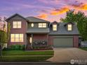 Charming two-story brick home featuring an attached two-car garage at sunset at 1141 Jefferson Dr, Berthoud, CO 80513