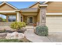 Welcoming front entrance featuring a covered porch, decorative wreath, and professionally landscaped flower beds at 11731 Center Dr, Longmont, CO 80504