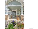 Inviting front porch with stone pillars, flowers, and a welcoming entrance to the home at 123 Ortega Ct, Erie, CO 80516