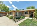 A single-story home featuring a long sunroom, brick facade, well-maintained landscaping, and an attached garage at 1235 Lincoln St, Longmont, CO 80501