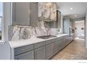 Modern kitchen with gray cabinetry, quartz countertops, stainless steel appliances, and marble backsplash at 12917 Fox St, Westminster, CO 80234