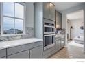Elegant kitchen featuring stainless steel appliances, gray cabinets, and marble accents, adjacent to a cozy living space at 12917 Fox St, Westminster, CO 80234