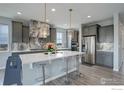 Modern kitchen with gray cabinetry, quartz countertops, stainless steel appliances, and stylish pendant lighting at 12917 Fox St, Westminster, CO 80234