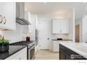 Well-equipped kitchen with stainless steel appliances, island, and white and black color scheme at 1611 Poplar Dr, Erie, CO 80516