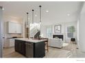Open-concept kitchen and living room with white finishes, modern fireplace, and sleek staircase at 1611 Poplar Dr, Erie, CO 80516