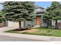 Charming two-story home with sage siding, an orange front door, mature trees, a manicured lawn and a driveway at 1695 Parkside Cir, Lafayette, CO 80026