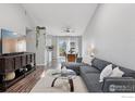 Sun-filled living room boasts vaulted ceilings, a modern sofa, hardwood floors, and access to the backyard at 1695 Parkside Cir, Lafayette, CO 80026