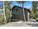 Picturesque two-story home with black exterior and decks nestled among trees at 1750 Deer Trail Rd, Boulder, CO 80302
