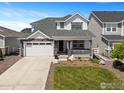 Charming two-story home with stone accents, a covered porch, landscaped yard, and an attached two-car garage at 1923 High Plains Dr, Longmont, CO 80503