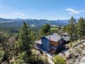 Aerial view of rustic home surrounded by mature trees with mountain views in the background at 22598 Westview Ave, Golden, CO 80401
