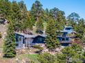 Exterior view of mountain home surrounded by mature trees and rocky landscape at 22598 Westview Ave, Golden, CO 80401