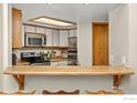 A view of the kitchen with wood cabinets, stainless appliances, and a peninsula at 2962 Shadow Creek Dr # 308, Boulder, CO 80303