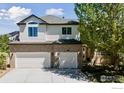 Two-story home with neutral siding and brick accents, three car garage and wide driveway at 3931 Stonegrass Pt, Broomfield, CO 80023