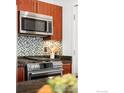 Close-up of a modern kitchen with stainless steel appliances, custom tile backsplash, and dark countertops at 4555 13Th St # 2C, Boulder, CO 80304