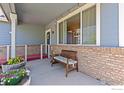 Cozy front porch featuring a wooden bench, brick accents, and decorative plants at 6054 Ulysses Ave, Firestone, CO 80504