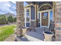 Cozy front porch featuring stone columns, rocking chairs, and a welcoming wreath on the door at 6212 Saddleback Ave, Firestone, CO 80504