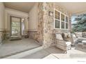 Inviting covered porch with stone accents, comfortable seating, and a view of the landscaped surroundings at 6542 S Tempe St, Aurora, CO 80016