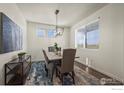 Bright dining room features a modern chandelier, large windows and neutral decor at 902 William Way, Brighton, CO 80603