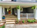 Inviting covered front porch with stone steps, hanging ferns, and outdoor seating, creating a cozy entrance at 982 Walnut Ct, Louisville, CO 80027