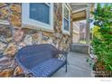 Inviting front porch with a cozy wicker bench, complemented by stone accents and lush greenery at 10048 Granby St, Commerce City, CO 80022