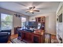 Well-lit office space with a large wooden desk, ceiling fan, and built-in shelving at 10048 Granby St, Commerce City, CO 80022