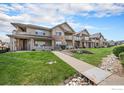 Condo building exterior with stone accents, a sidewalk, and landscaping at 10818 Cimarron St # 206, Firestone, CO 80504