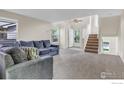 Inviting living room with staircase, neutral tones, and cozy seating area with ample natural light at 1724 Holeman Dr, Erie, CO 80516