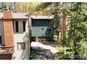 Multi-level home featuring a driveway leading to attached garages with a wooden walkway alongside surrounded by trees at 4888 Silver Spruce Ln, Evergreen, CO 80439