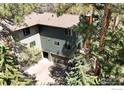 Multi-level home featuring attached garages with a wooden walkway alongside the building surrounded by trees at 4888 Silver Spruce Ln, Evergreen, CO 80439