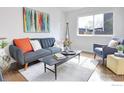 Bright living room with a stylish couch, colorful art, and hardwood flooring at 713 Arrow Ct, Lafayette, CO 80026