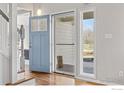 Bright entryway featuring hardwood floors, a blue front door, and staircase at 7430 Cardinal Ln, Longmont, CO 80503