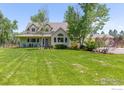 Inviting home with a lush lawn, mature trees, and charming front porch at 7430 Cardinal Ln, Longmont, CO 80503