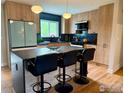 Modern kitchen featuring a spacious island with bar seating, wooden cabinetry, and stainless steel appliances at 815 S Jersey St, Denver, CO 80224