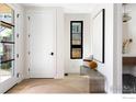 Bright foyer with white walls, wood floors, modern bench seating, and decorative artwork near half bathroom at 855 Eudora St, Denver, CO 80220