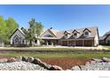 An impressive home shows stone accents, a manicured lawn, and a charming stone retaining wall near the driveway at 9833 Shoreline Dr, Longmont, CO 80504