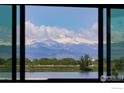 A scenic view framed by a window showing snow-capped mountains and a serene lake with lush trees at 9833 Shoreline Dr, Longmont, CO 80504