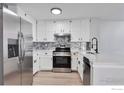 Updated kitchen with stainless steel appliances, white cabinets, countertops and mosaic backsplash at 12525 E Tennessee Cir # E, Aurora, CO 80012