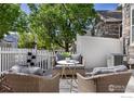 Back patio with comfortable wicker seating and privacy fence, perfect for outdoor relaxation at 14246 Pikeminnow Pl, Broomfield, CO 80023