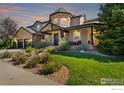 Charming home features a stone and stucco facade, well-manicured lawn, and inviting covered porch at 1702 Montgomery Cir, Longmont, CO 80504