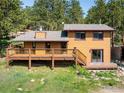 Rear exterior view showcases a brown house with a spacious wooden deck, complemented by well-maintained landscaping at 201 Wild Tiger Rd, Boulder, CO 80302