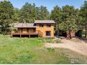 Back exterior view of a brown home with a wooden deck, nestled in a serene, green landscape at 201 Wild Tiger Rd, Boulder, CO 80302