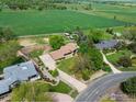 An aerial showcases a property with mature landscaping, a long driveway, and picturesque green surroundings at 2117 Stonehenge Cir, Lafayette, CO 80026