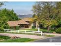 Beautiful home exterior featuring a well-manicured lawn, gravel driveway, and a charming white fence at 2117 Stonehenge Cir, Lafayette, CO 80026