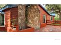Charming home exterior with a stone chimney, beautiful wood deck, and mature tree growing on deck at 23891 Supai Rd, Indian Hills, CO 80454