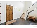 Bright foyer with a wooden front door, staircase, dark hardwood floors, and white walls at 3219 7Th St, Boulder, CO 80304