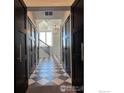 Elegant foyer with black paneled doors, decorative light fixture, and tile flooring leading to the staircase at 410 Superior Dr, Superior, CO 80027