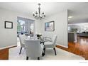 Elegant dining room with a modern chandelier, glass-top table, and access to the living room, ideal for gatherings at 6105 El Diente Cir, Golden, CO 80403