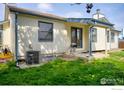 Backyard featuring green grass, home exterior, and a grill on a small patio at 730 Douglas Pl, Berthoud, CO 80513